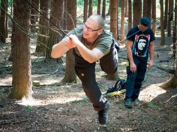 Mann überquert selbstgebaute Seilbrücke zwischen Bäumen im Wald