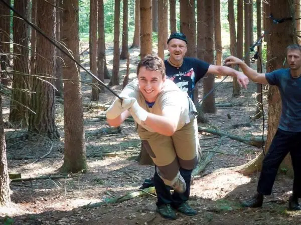 Mann überquert selbstgebaute Seilbrücke zwischen Bäumen im Wald