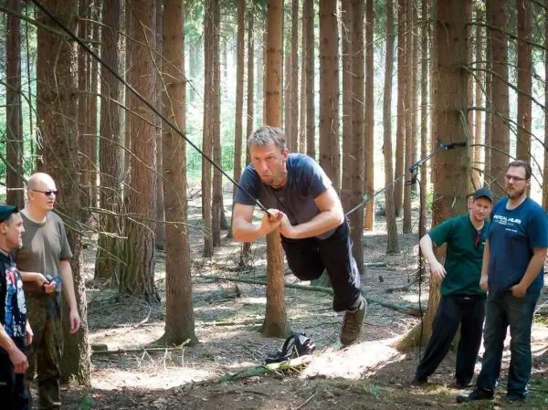 Mann überquert selbstgebaute Seilbrücke zwischen Bäumen im Wald