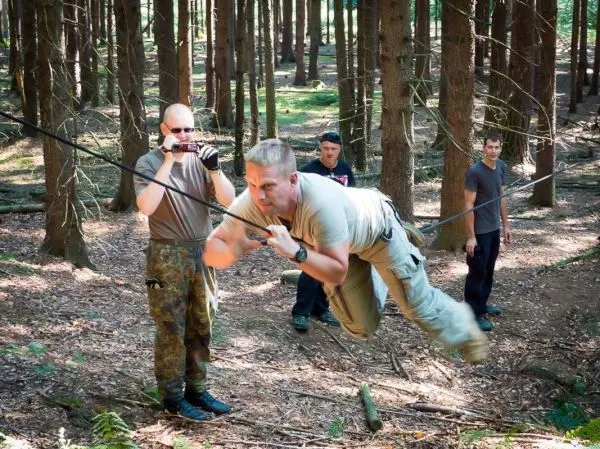 Mann überquert selbstgebaute Seilbrücke zwischen Bäumen im Wald