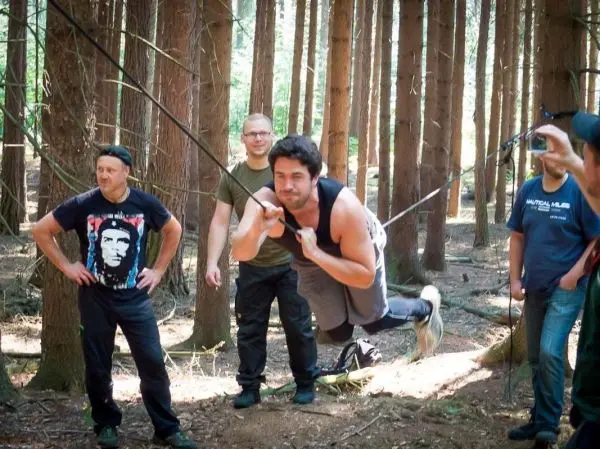 Mann überquert selbstgebaute Seilbrücke zwischen Bäumen im Wald