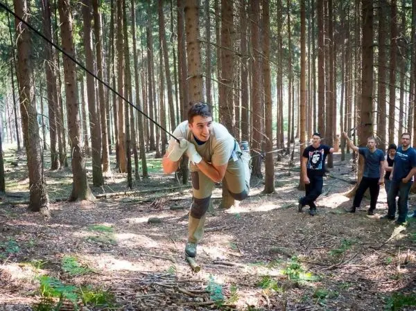 Mann überquert selbstgebaute Seilbrücke zwischen Bäumen im Wald