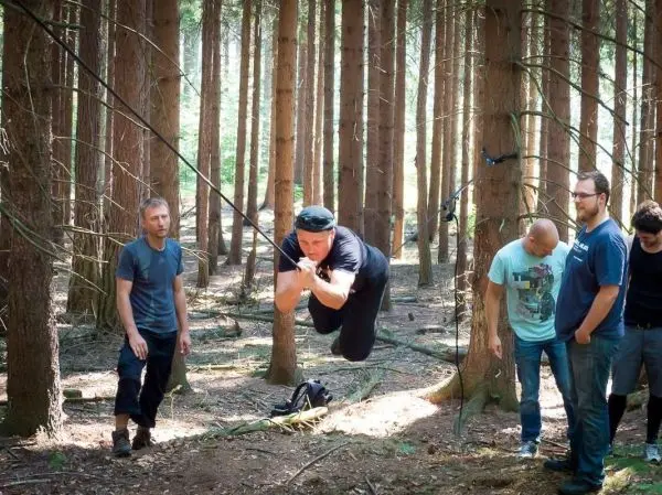 Mann überquert selbstgebaute Seilbrücke zwischen Bäumen im Wald