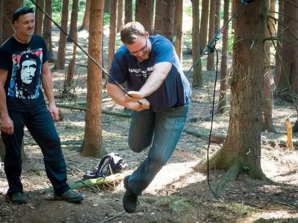 Mann überquert selbstgebaute Seilbrücke zwischen Bäumen im Wald