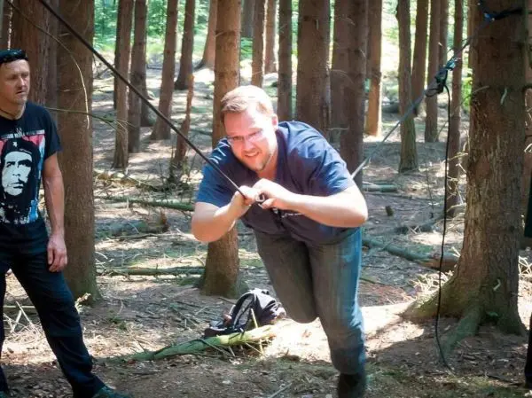 Mann überquert selbstgebaute Seilbrücke zwischen Bäumen im Wald