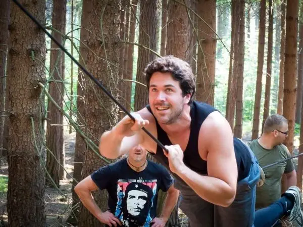 Mann zieht an einem Seil in einem Waldgebiet