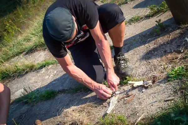 Person bereitet Zunder zum Feuermachen vor beim Survival Training