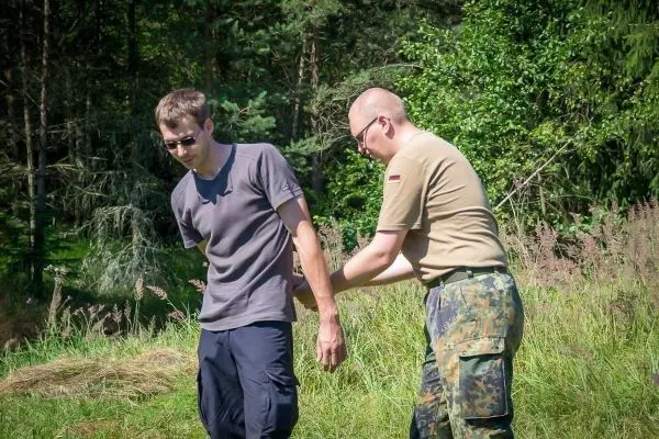Person hilft anderer Person beim Anlegen einer Bandage im Freien