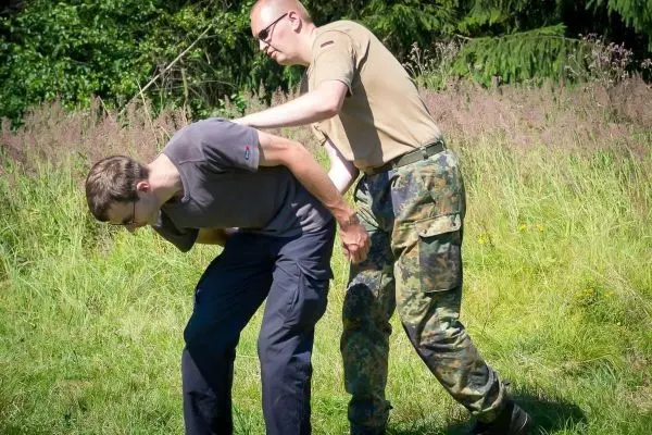 Person hilft anderer Person beim Üben einer Technik im Freien