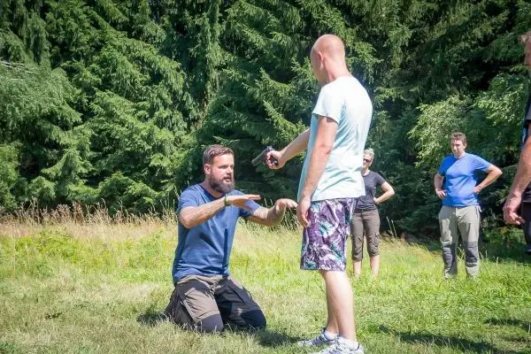 Person kniet und erklärt einer anderen Person eine Technik im Freien