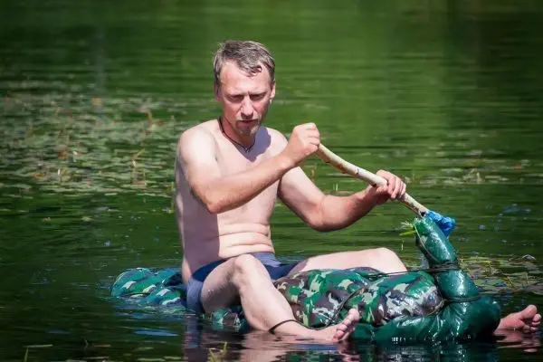 Person paddelt auf einer selbstgebauten Schwimmhilfe im Wasser