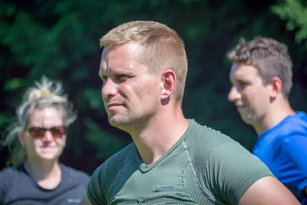 Person schaut nachdenklich in die Ferne, andere Personen im Hintergrund