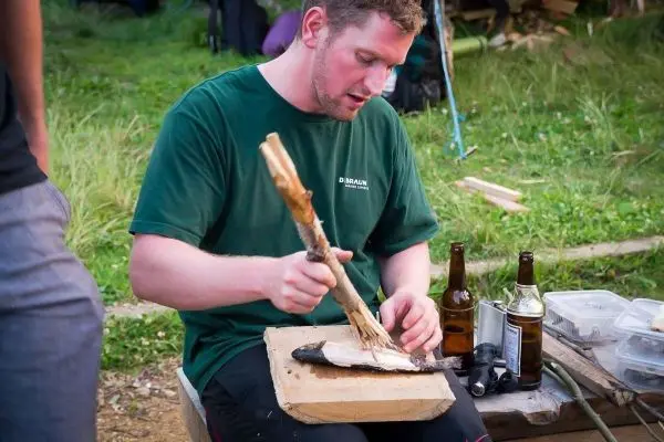 Person schneidet Fisch auf einem Holzbrett