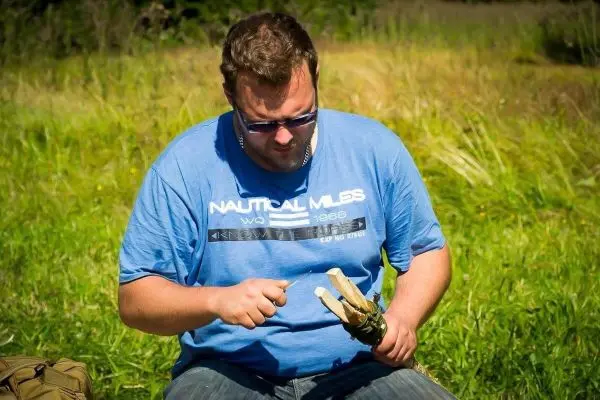 Person schnitzt mit einem Messer an einem Holzstück