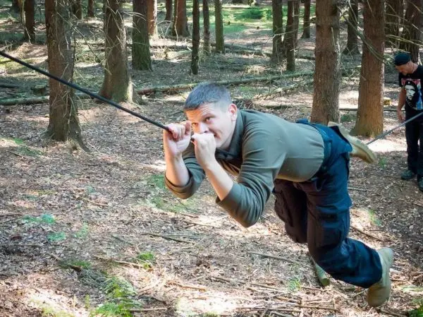 Person schwingt an einem Seil durch den Wald beim Überlebenstraining