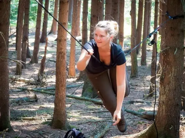 Person schwingt an einem Seil zwischen Bäumen beim Überlebenstraining