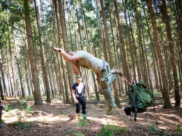 Person schwingt an Seil über den Boden im Wald