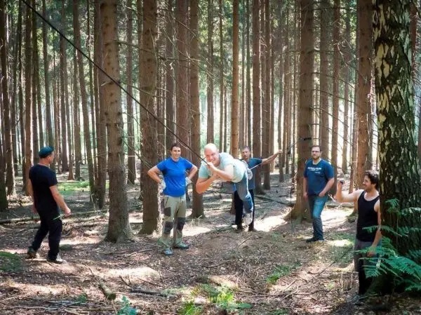 Person schwingt an Seil zwischen Bäumen im Wald beim Survival Training