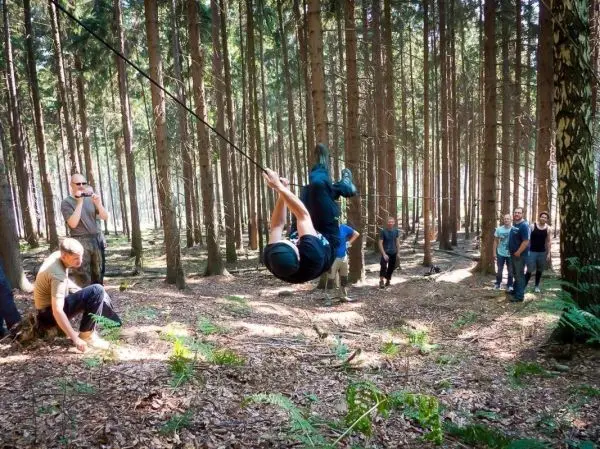 Person schwingt an Seil zwischen Bäumen im Wald beim Survival Training