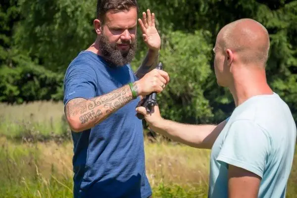 Person zeigt eine Waffe auf eine andere Person beim Training