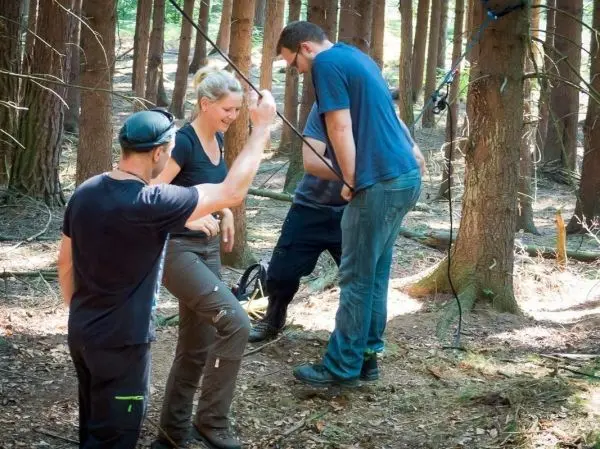 Personen arbeiten an einer selbstgebauten Seilbrücke im Wald