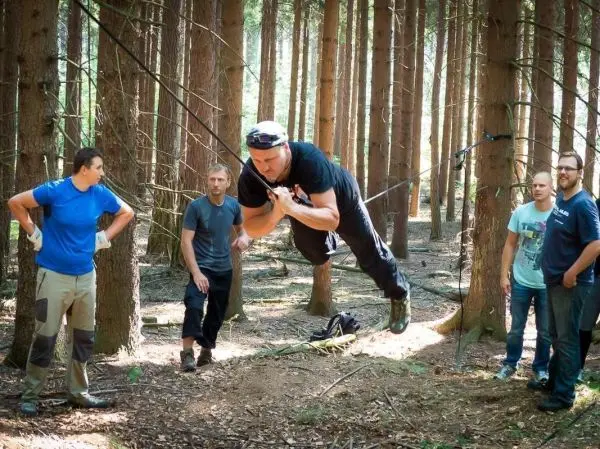 Selbstgebaute Seilquerung wird von einer Person überquert, während andere zuschauen
