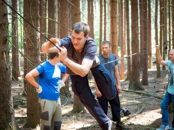 Teilnehmer überquert eine selbstgebaute Seilbrücke zwischen Bäumen
