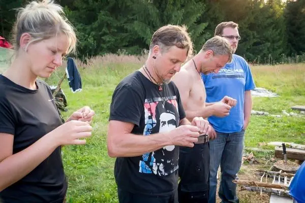 Vier Personen konzentrieren sich auf das Bearbeiten von Materialien im Freien