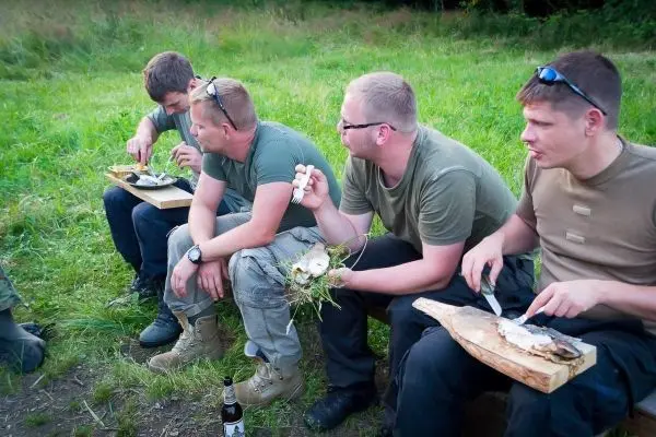 Vier Personen sitzen auf einer Bank und essen aus Holzplatten