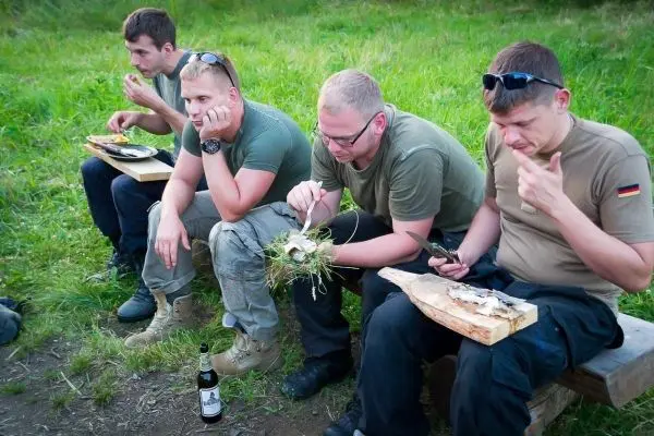 Vier Personen sitzen auf einer Bank und essen zubereiteten Fisch