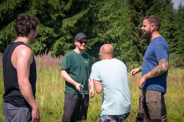 Vier Personen stehen in einer Wiese und unterhalten sich