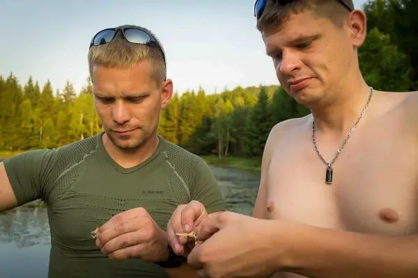 Zwei Männer halten kleine Objekte in den Händen und betrachten sie aufmerksam