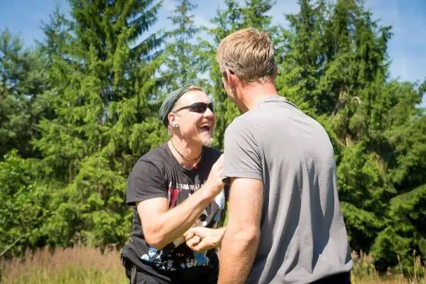 Zwei Männer lachen und interagieren in einer Waldumgebung
