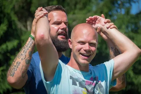 Zwei Männer stehen in einer Umarmung, einer hält den anderen am Kopf