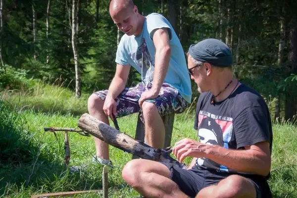 Zwei Personen arbeiten an einer selbstgebauten Konstruktion aus Holzstücken im Freien
