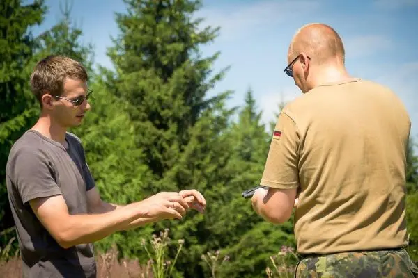 Zwei Personen stehen im Freien und diskutieren über ein Gerät