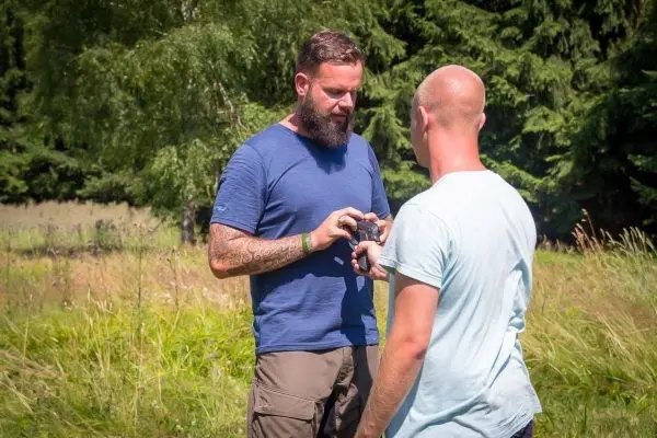 Zwei Personen stehen in einer Wiese und betrachten ein Objekt in der Hand