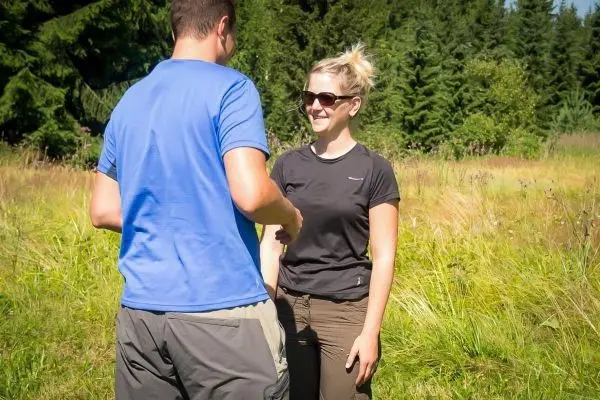 Zwei Personen stehen in einer Wiese und unterhalten sich