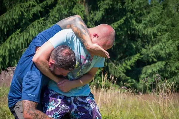 Zwei Personen üben eine Kampfsporttechnik im Freien aus