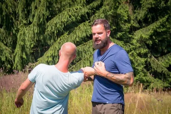 Zwei Personen üben eine Selbstverteidigungstechnik im Freien