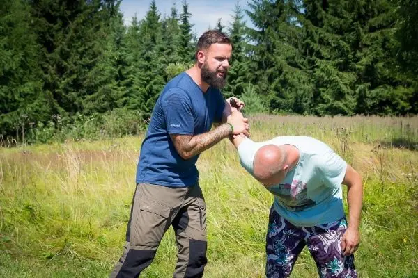 Zwei Personen üben eine Selbstverteidigungstechnik im Freien aus