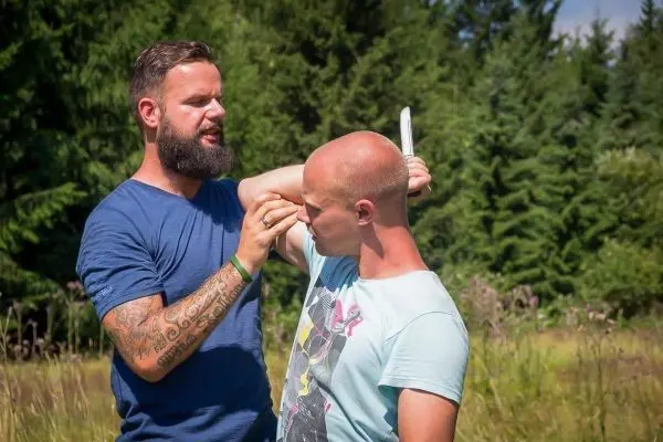 Zwei Personen üben eine Selbstverteidigungstechnik im Freien mit einem Messer