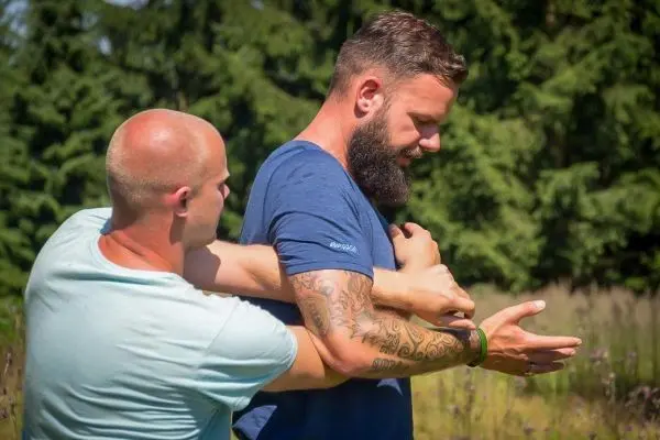 Zwei Personen üben eine Technik zur Kontrolle des Arms in einer natürlichen Umgebung