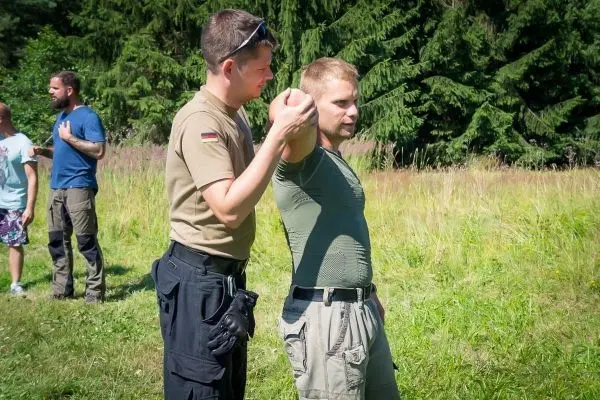 Zwei Personen üben eine Technik zur Kontrolle eines Arms im Freien