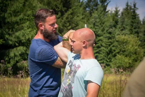 Zwei Personen üben eine Technik zur Selbstverteidigung im Freien