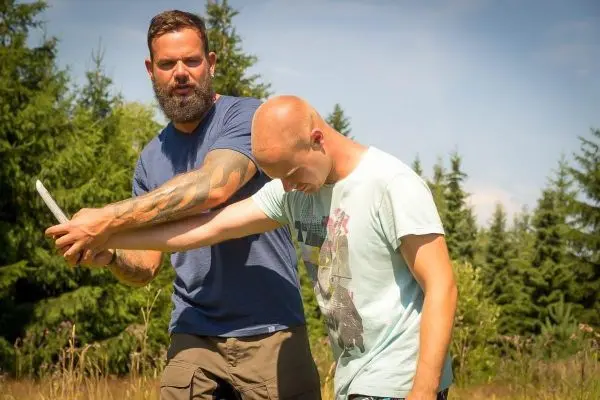 Zwei Personen üben eine Technik zur Selbstverteidigung im Freien