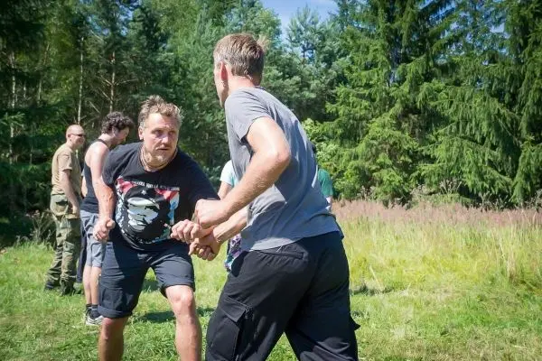 Zwei Personen üben einen Handkampf in einer grünen Wiese
