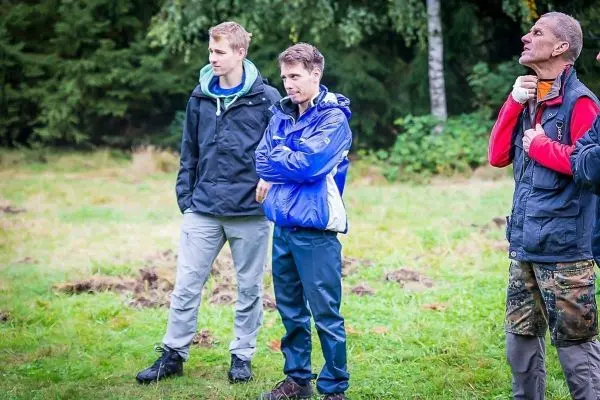 Drei Personen stehen auf einer Wiese und beobachten etwas