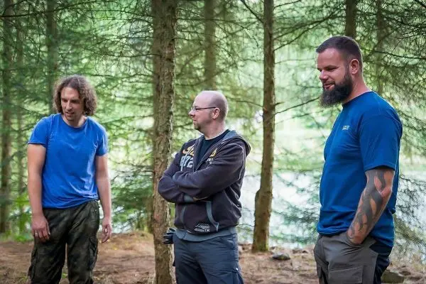 Drei Personen stehen im Wald und unterhalten sich