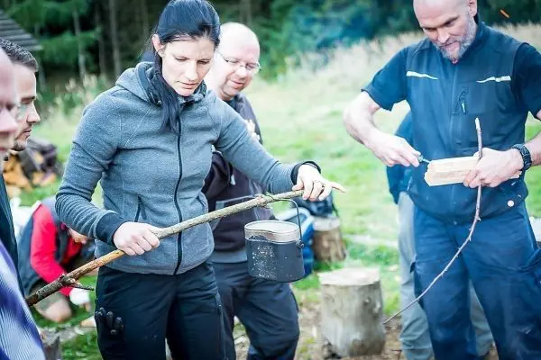 Frau hält einen Kessel mit einem Stock über ein Feuer